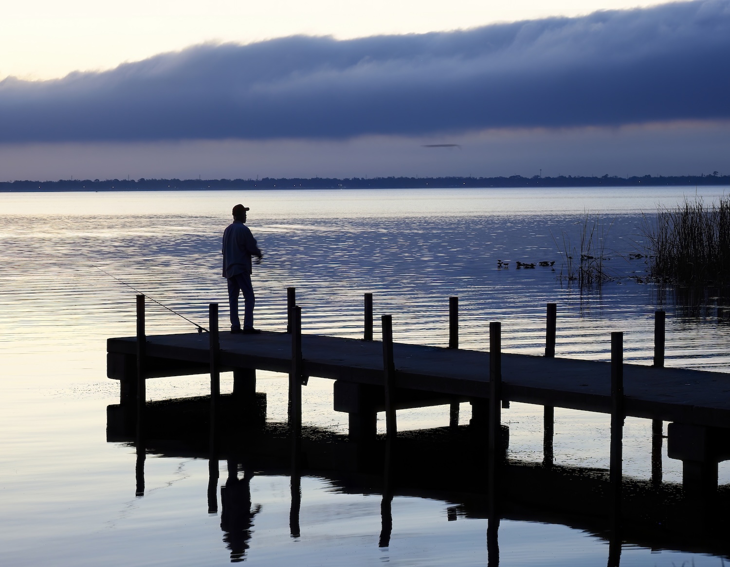  Single Fisherman Stands on the Dock Fishing in Pre Dawn Light